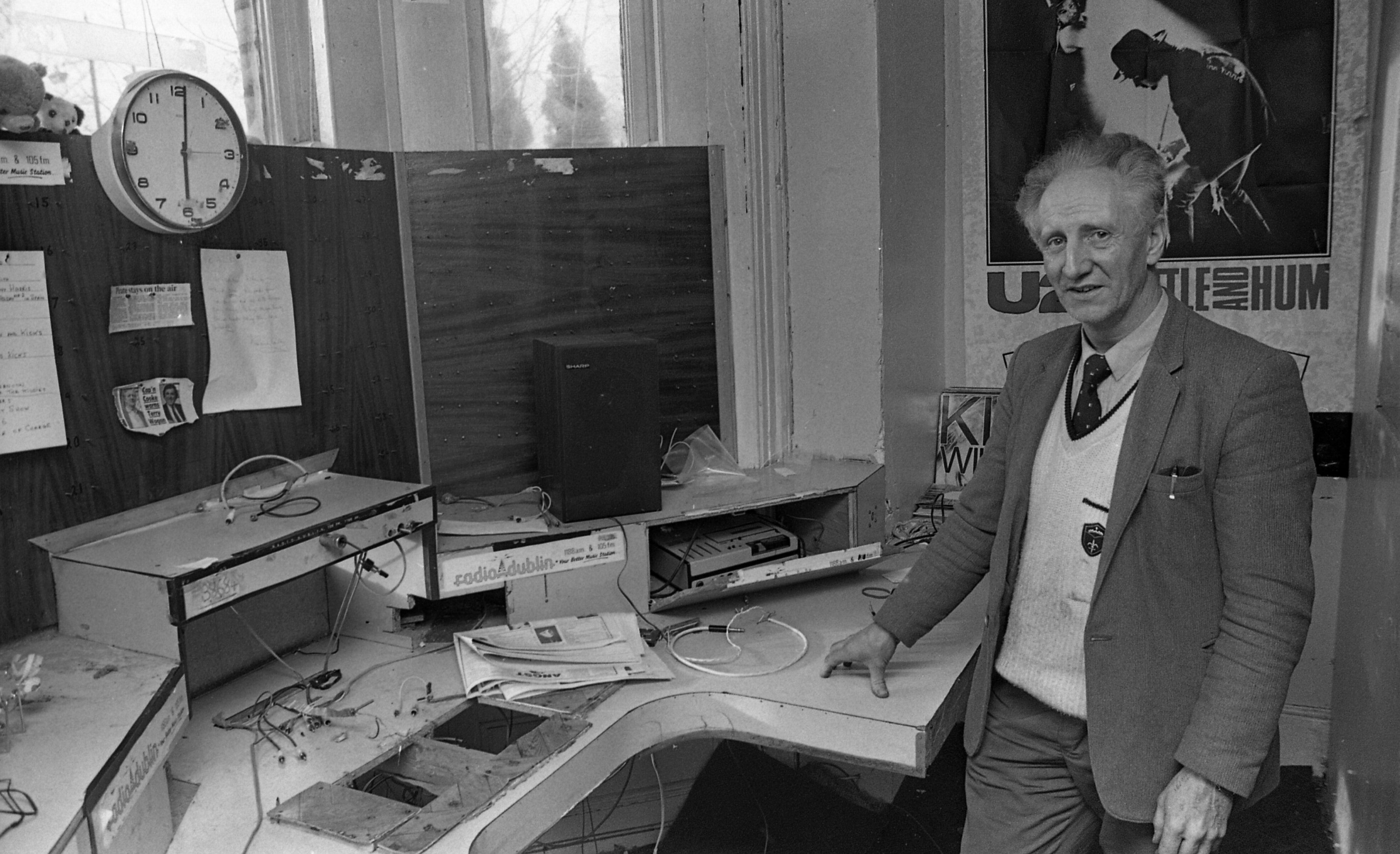 Black and white image of man standing at a desk with radio equipment